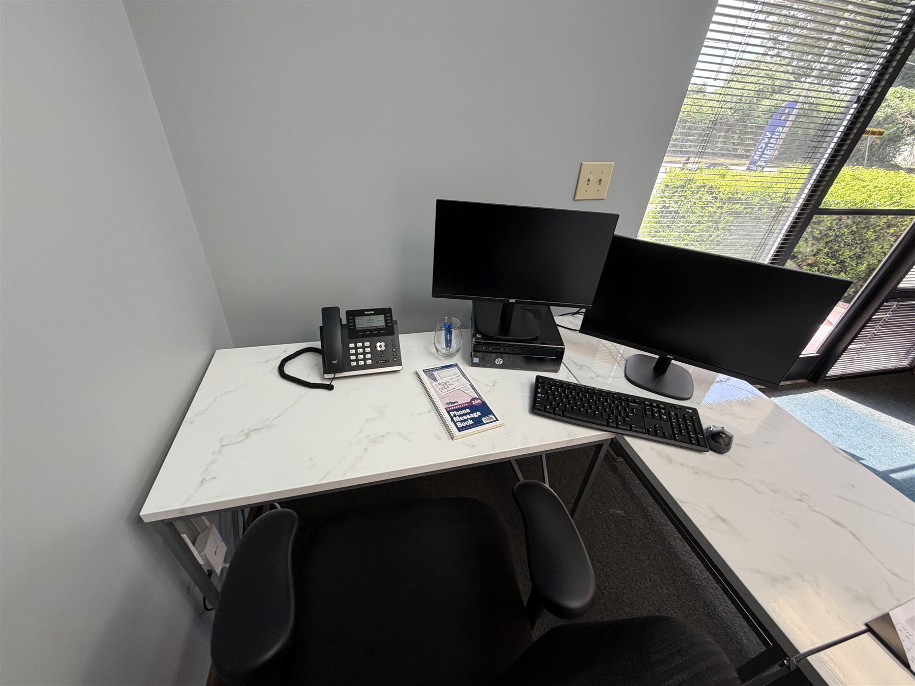 A finished office workstation with a Yealink phone and dual monitors set up by Unified Telecom