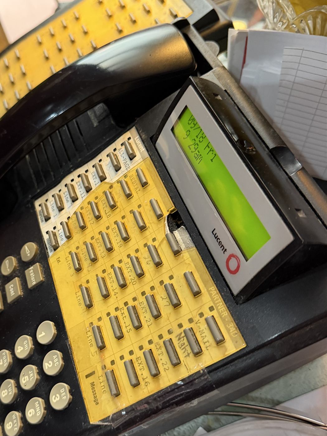 A worn Lucent Partner key-system phone with faded, taped-on extension labels